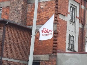 Przy murze zakładu salezjańskiego powiewa flaga z napisem 89 2019 Oświęcim