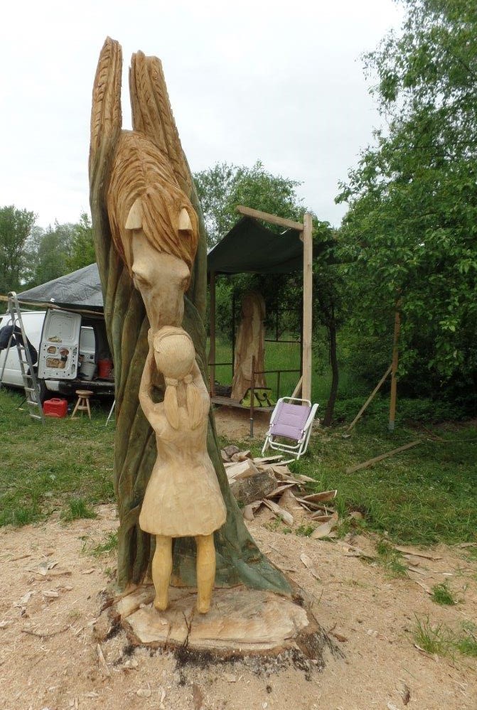 Rzeźba w pniu drzewa przedstawia konia i dziewczynkę