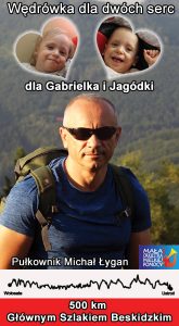 Na zdjęciu Michał Łygan w górach. Napis Wędrówka dla dwóch serc dla Gabrielka i Jagódki 