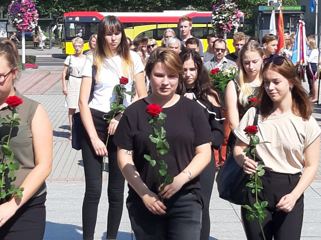 Młodzież składa czerwone róże
