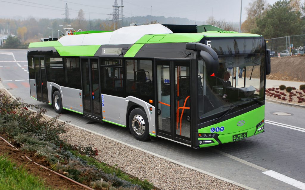Zielony autobus elektryczny jedzie przez rondo