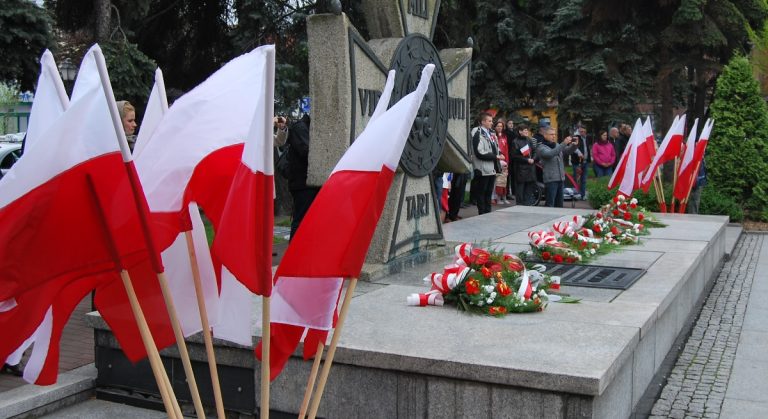 Grób Nieznanego Żołnierza. Na płycie leżą kwiaty, obok stoją flagi biało-czerwone
