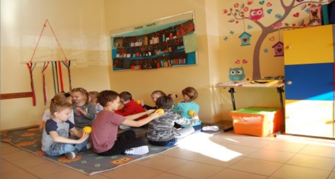 Uczniowie siedzą na dywanie