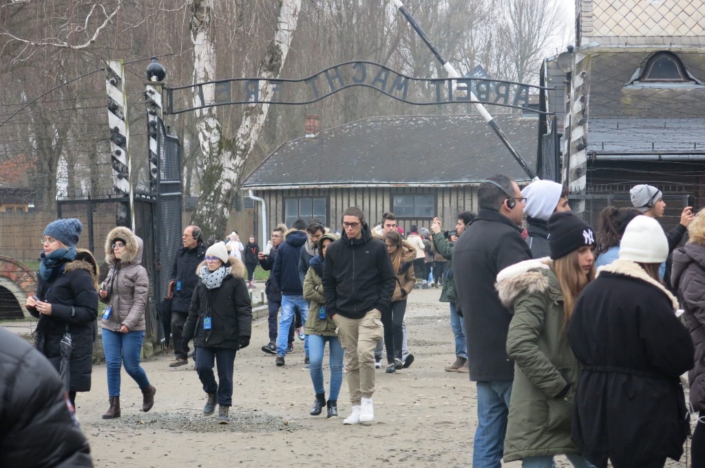 Zwiedzający Muzeum Pamięci Auschwitz -Birkeanu przechodzą przez bramę z napisem Arbeit macht frei