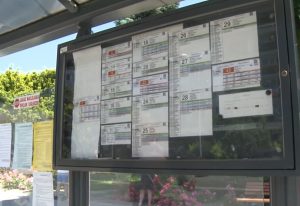 Na przystanku autobusowym  widać dużą tablicę z rozkładami jazdy autobusów