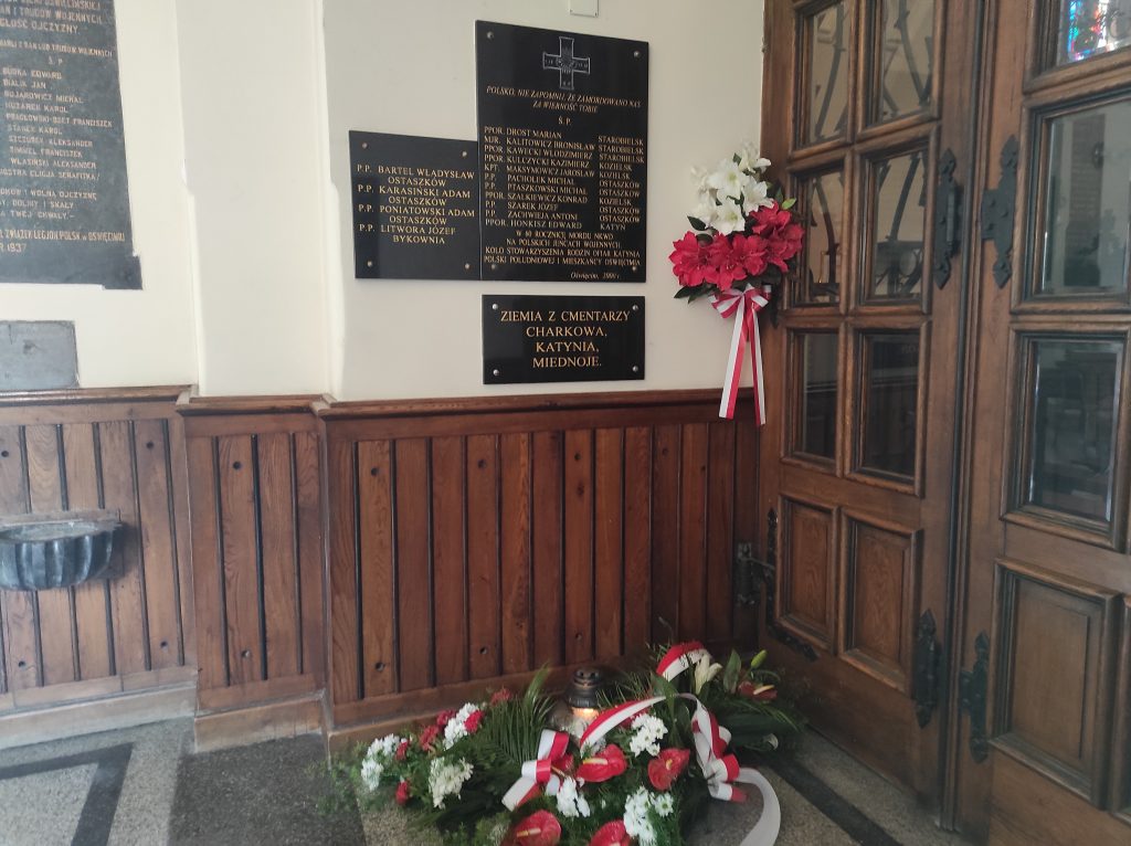 Wiązanki kwiatów pod tablicą upamietniającą ofiary zbrodni katyńskiej, mieszkańców ziemi oświęcimskiej