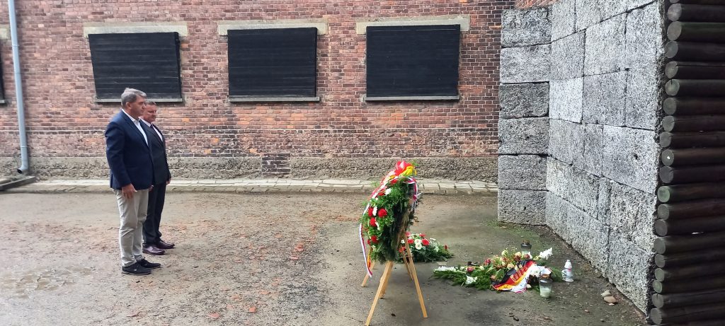 Prezydent w towarzystwie radnego składa kwiaty przy Ścianie Śmierci w KL Auschwitz