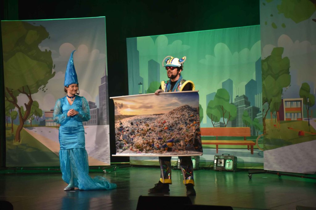 Aktorzy w barwnych kostiumach prezentują jak wygląda zanieczyszczona ziemia