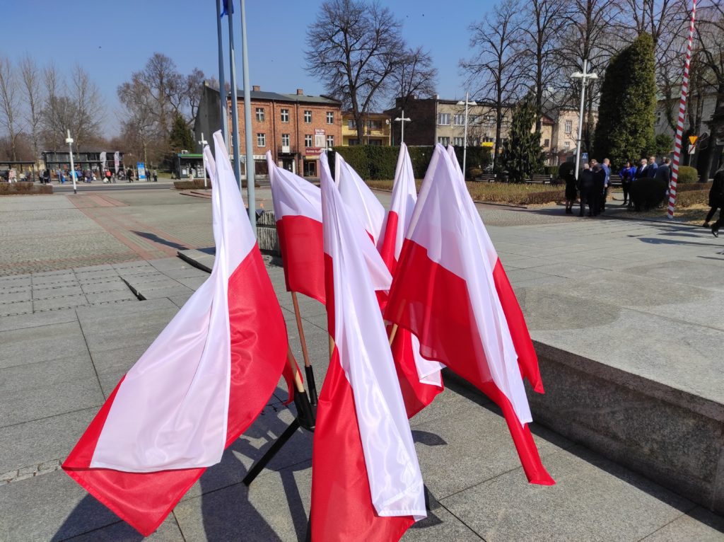 Biało-czerwone flagi w stojaku łopoczą na wietrze