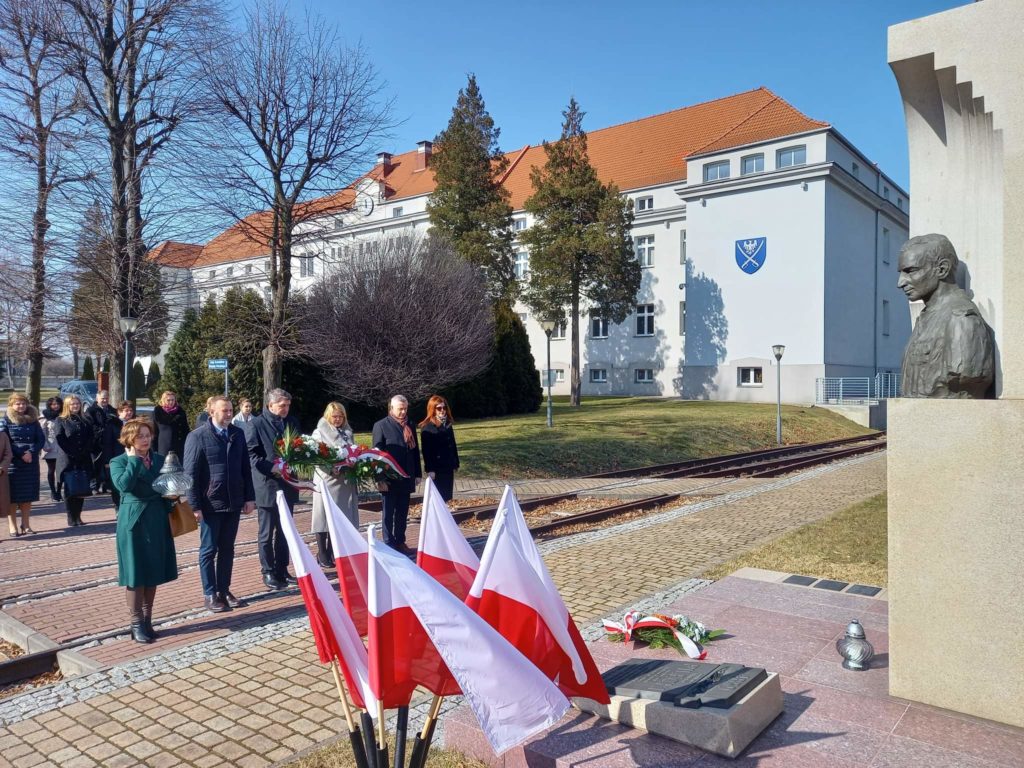 Przed pomnikiem rtm. Witolda Pileckiego stoi delegacja z kwiatami