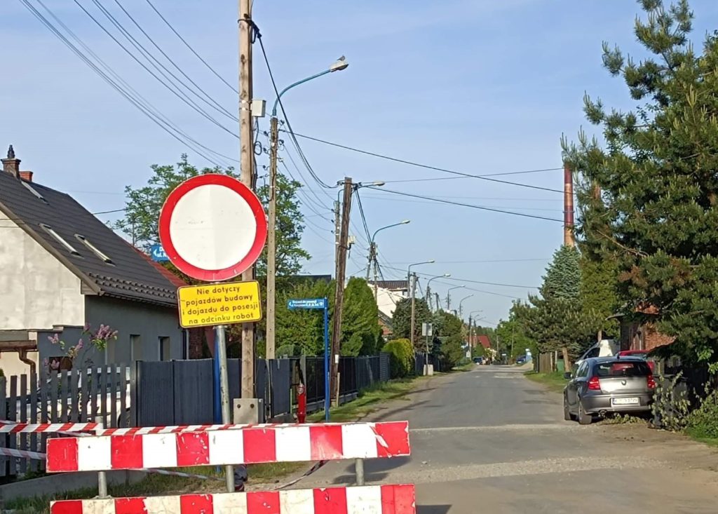 Na pierwszym planie widać barierki i znak drogowy zakaz wjazdu na przebudowywaną ulicę Koszykową