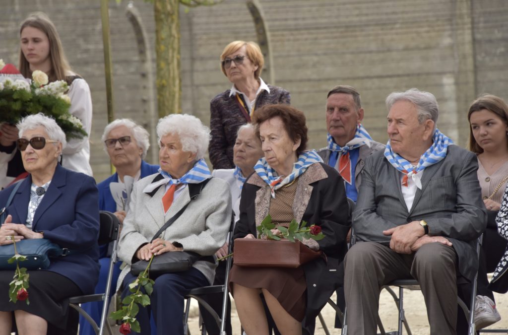 Byli więźniowie KL Auschwitz podczas uroczystości siedzą i słuchają przemówień