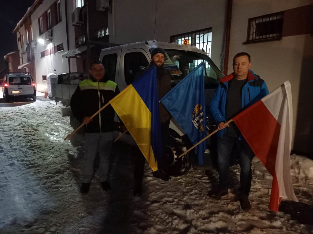 Delegacja oświęcimska z flagami Polski, Ukrainy i miasta Oświęcimia przed budynkiem PEC