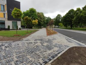 Droga wraz z chodnikiem przy niej szpaler drzew i fragment hotelu Olimpijskiego