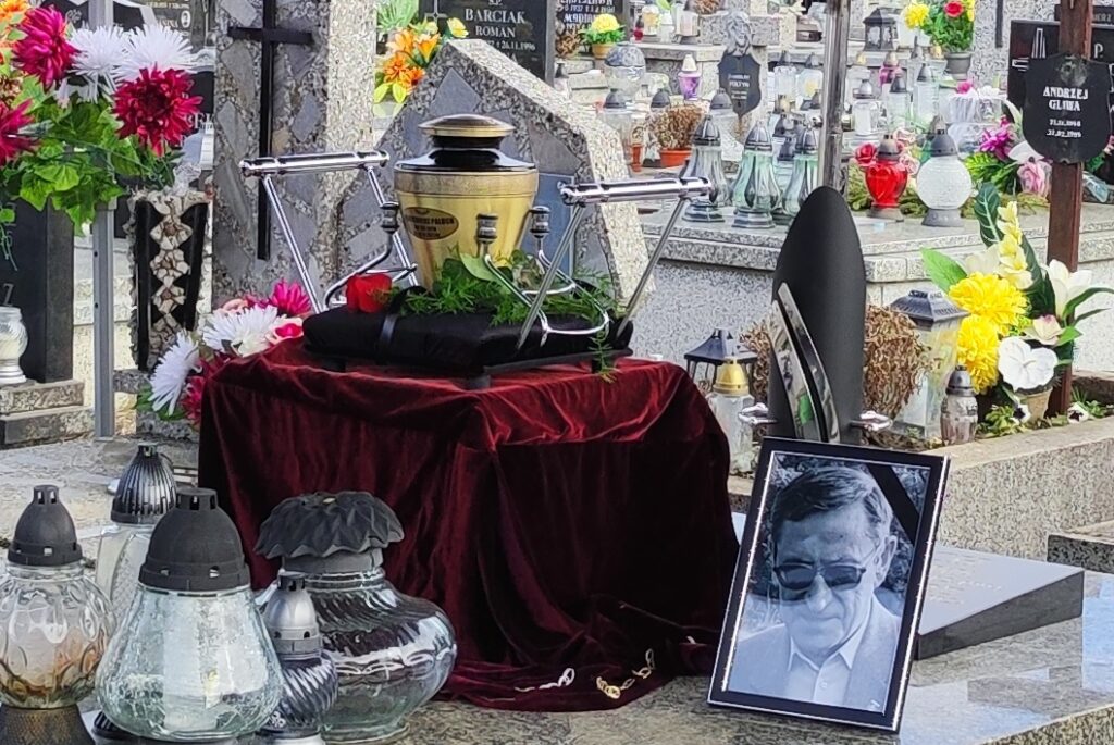 Zdjęcia, urna z prochami i wieńce od żałobników na grobowcu